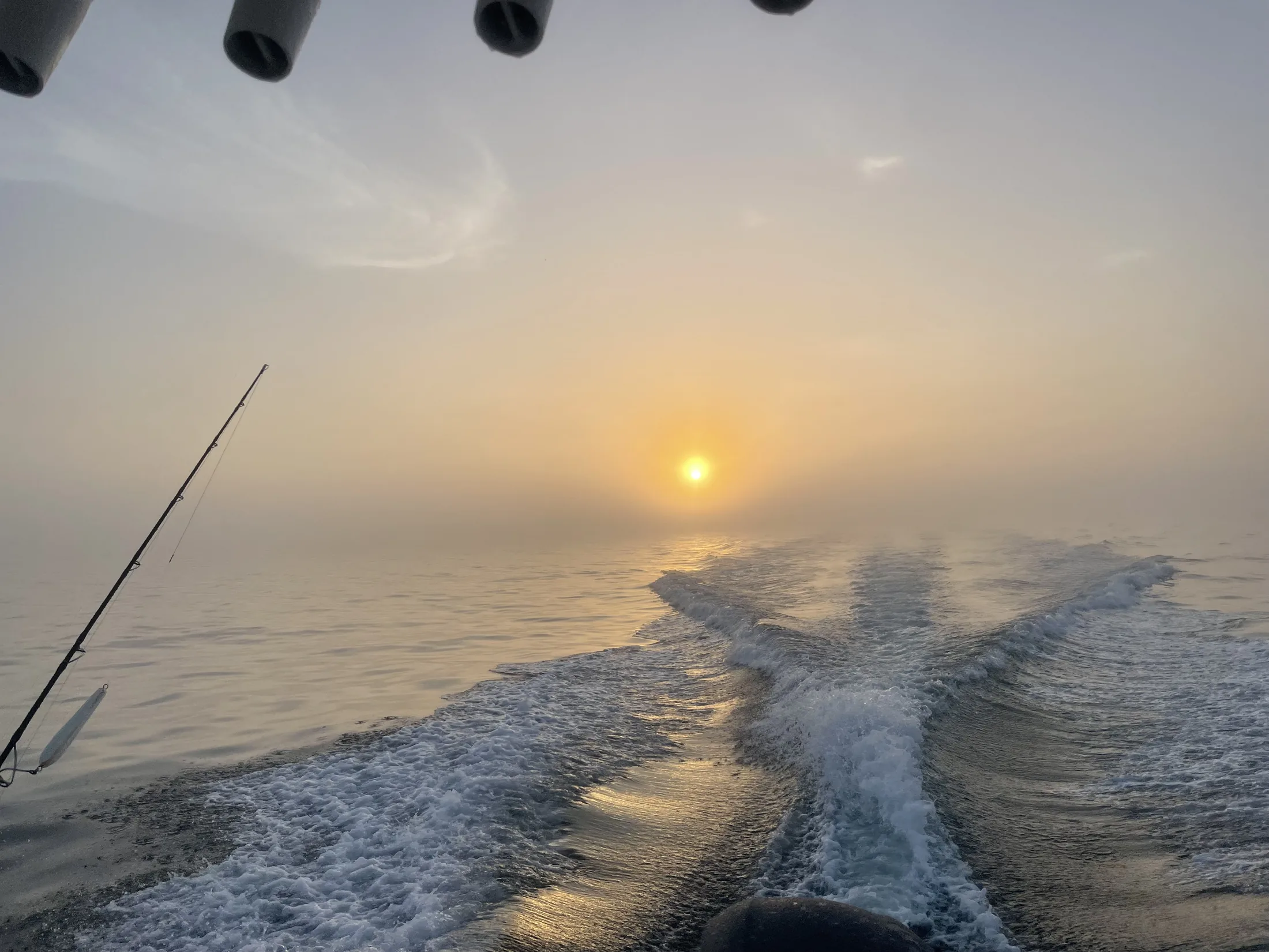 Boat wake beneath a dramatic sunset sky